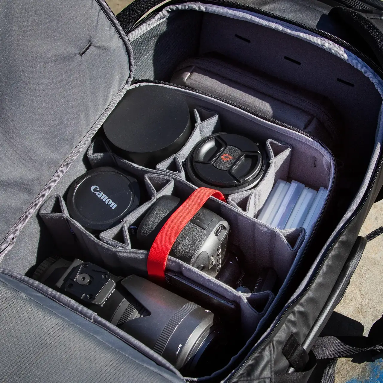 Camera bag with compartments for camera equipment, including lenses and a Canon logo.