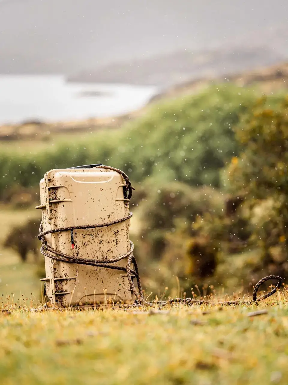 Mud-covered cooler in a grassy field with a blurred background