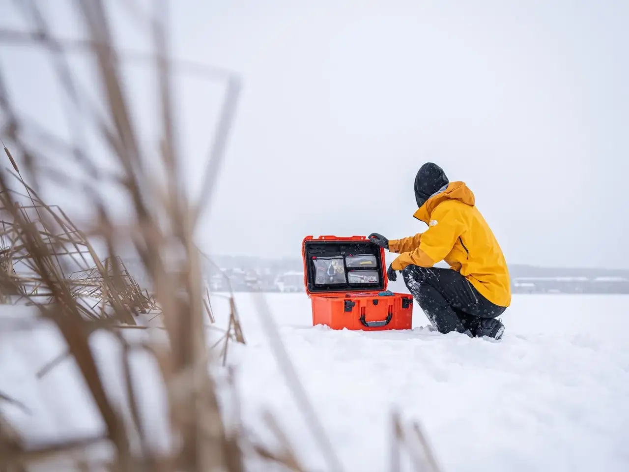 Person in yellow jacket with equipment in snowy landscape