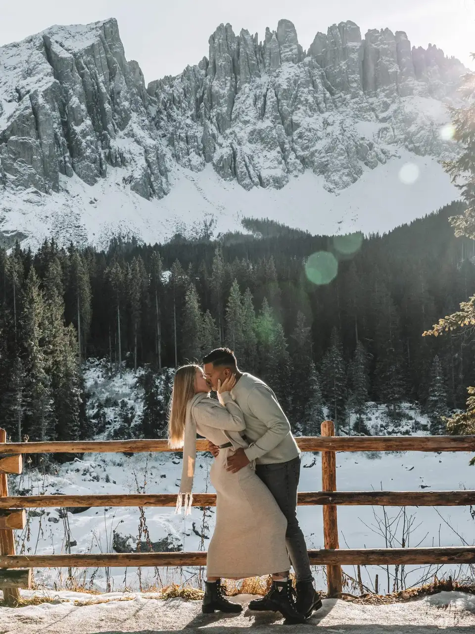 Couple embracing in a snowy landscape with mountains and trees in the background