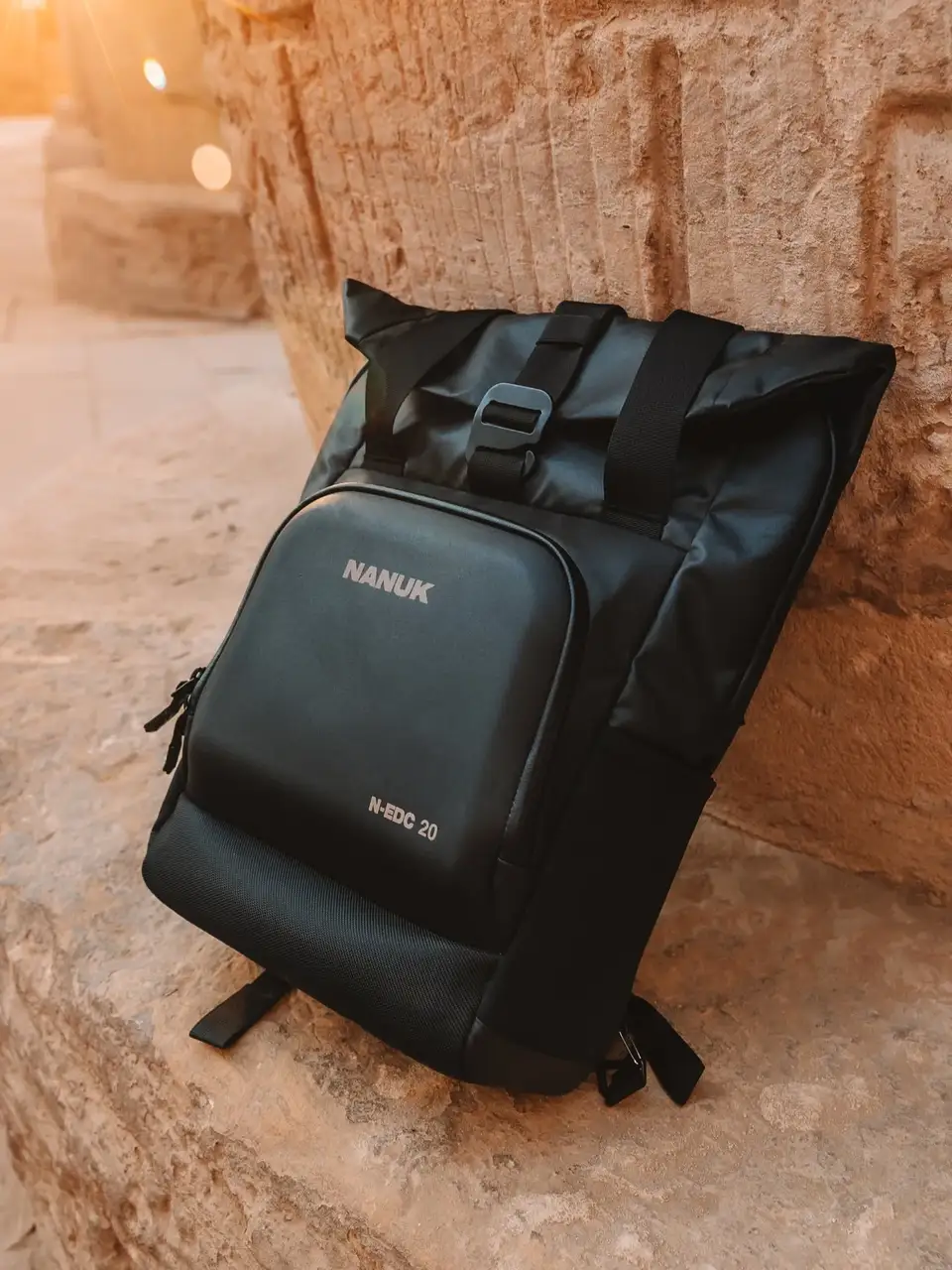 Black backpack with 'JunZhiJia' branding on a stone surface