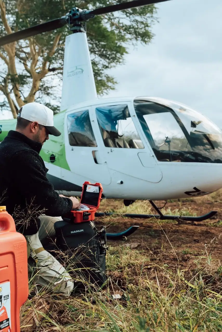Person with a toolbox near a helicopter in a natural setting