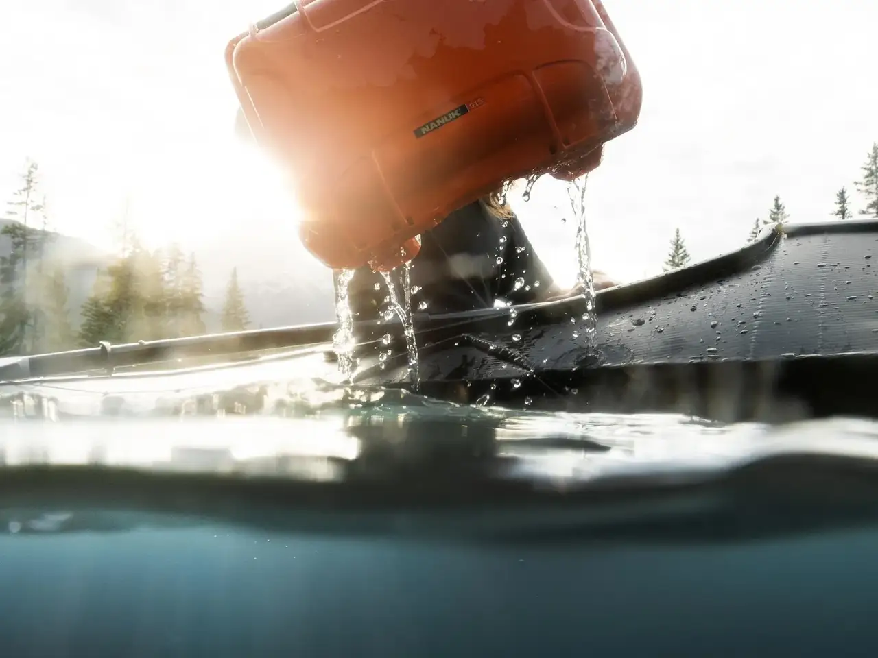 Orange car wash brush being used on a car's windshield with trees in the background