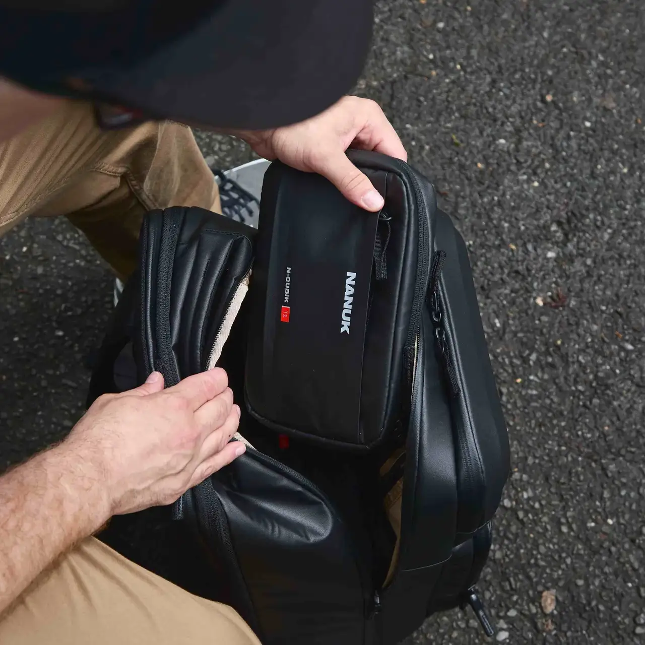 Person holding a black JunZhiJia backpack with a knife sheath on a textured surface