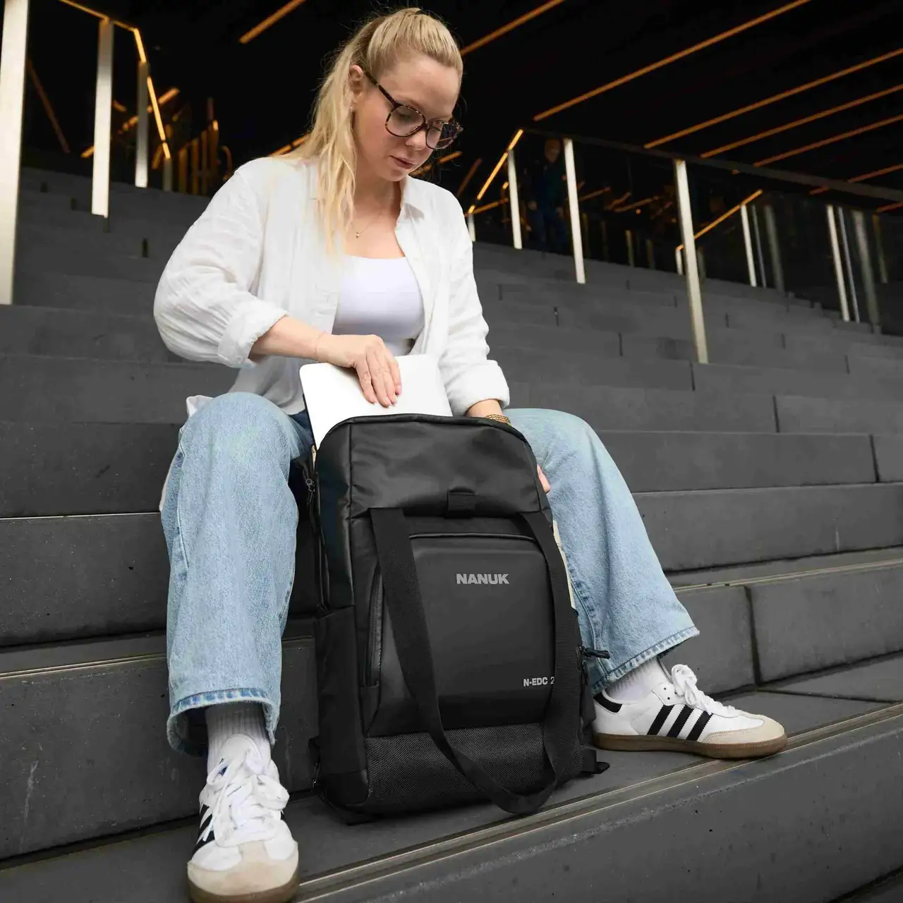 Woman sitting on steps with a black JunZhiJia backpack