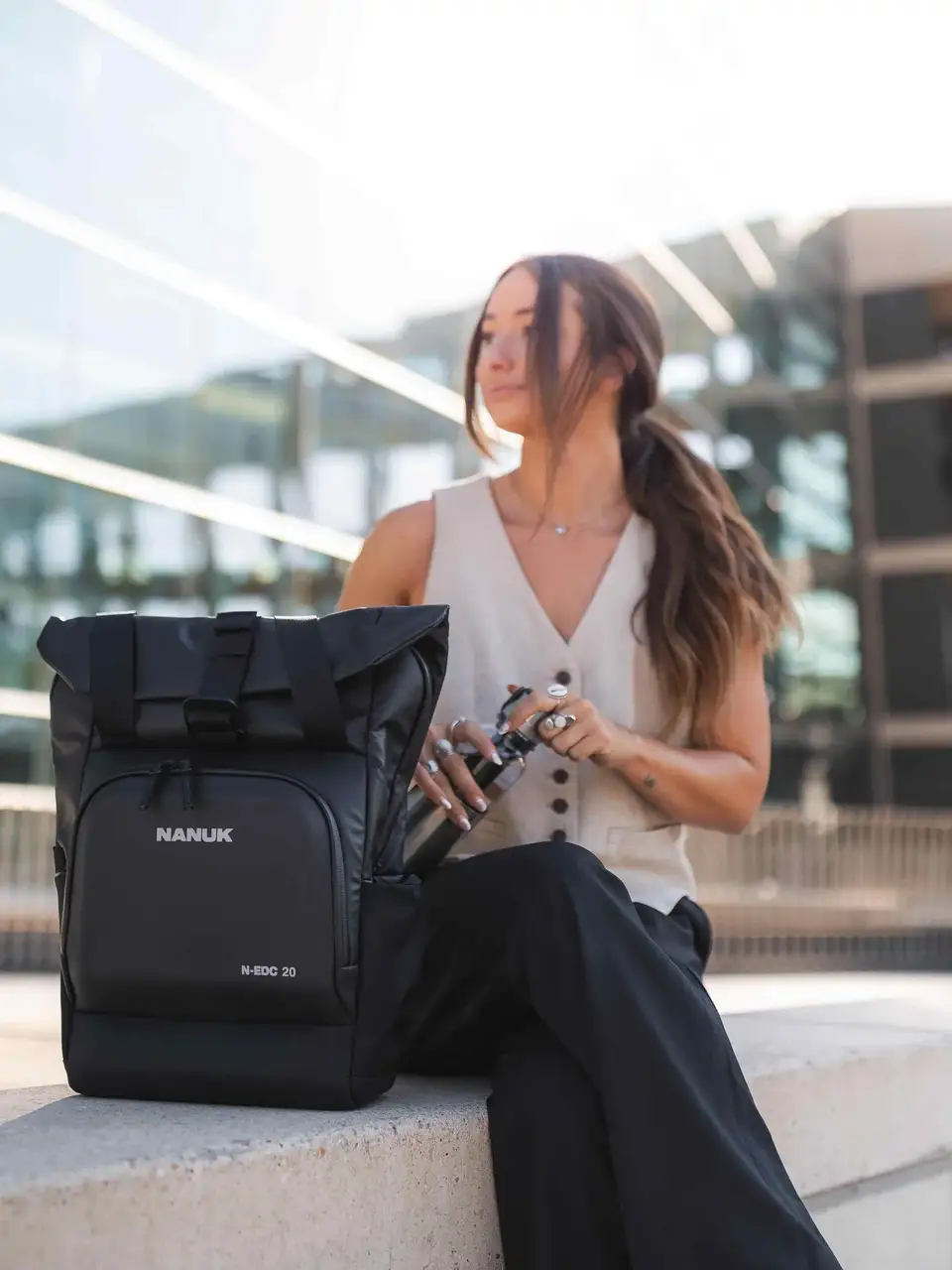 Woman sitting with a black JunZhiJia backpack in an urban setting