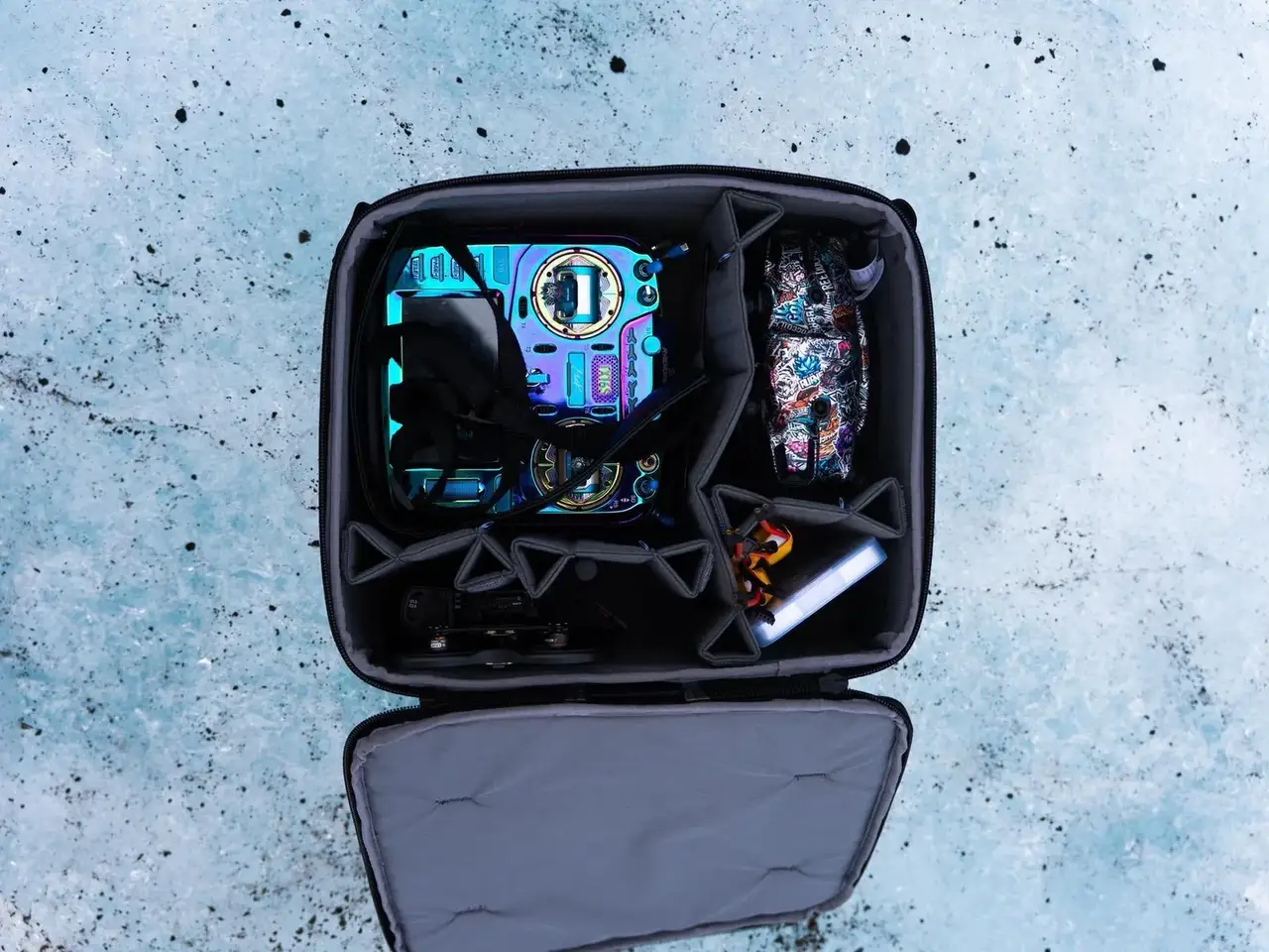 Open black camera bag with camera equipment on a textured blue surface