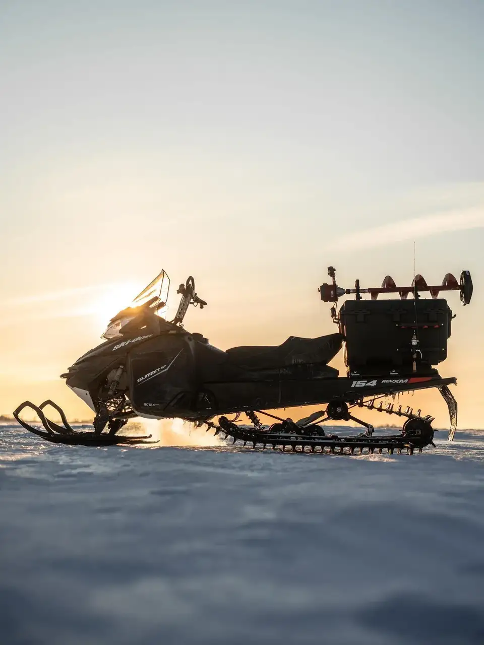 Snowmobile on a snowy landscape with a sunset sky