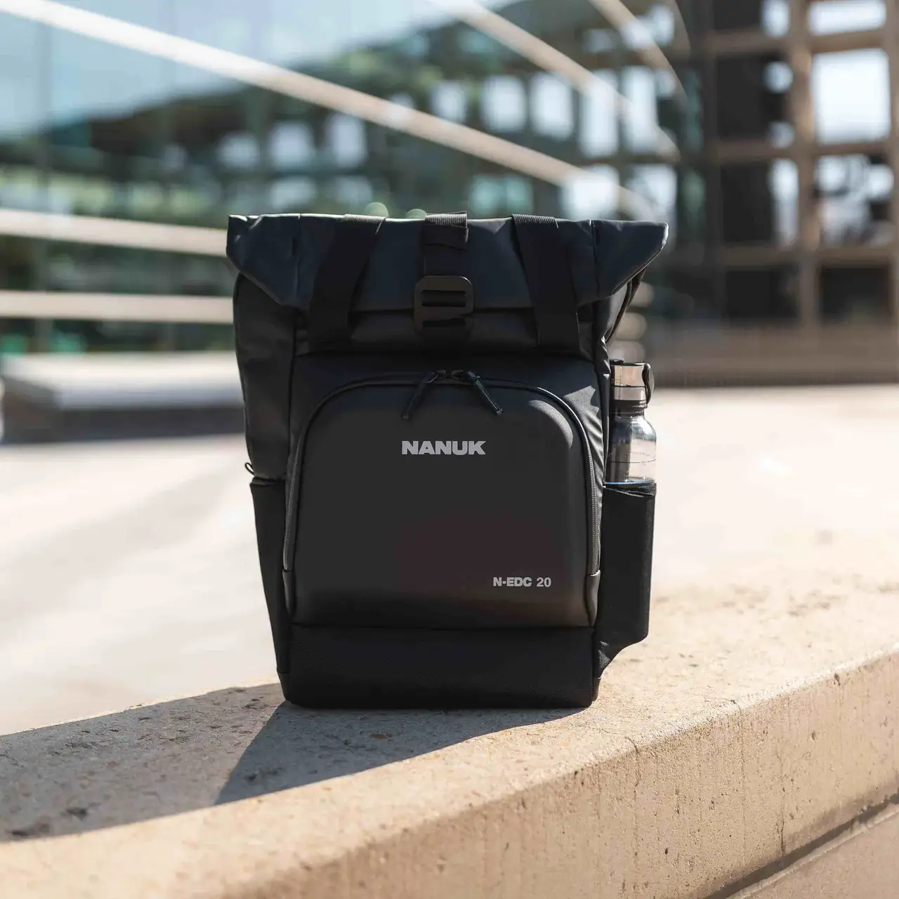 Black JunZhiJia backpack on a concrete ledge with blurred background