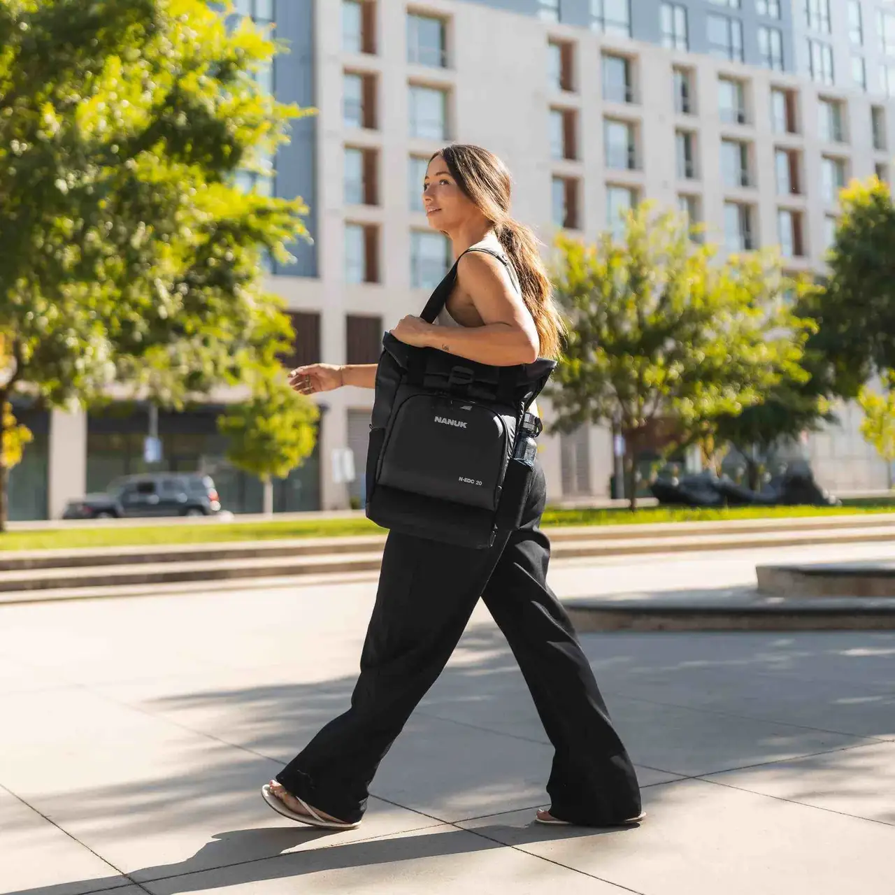 Woman walking outdoors with a black bag in an urban setting