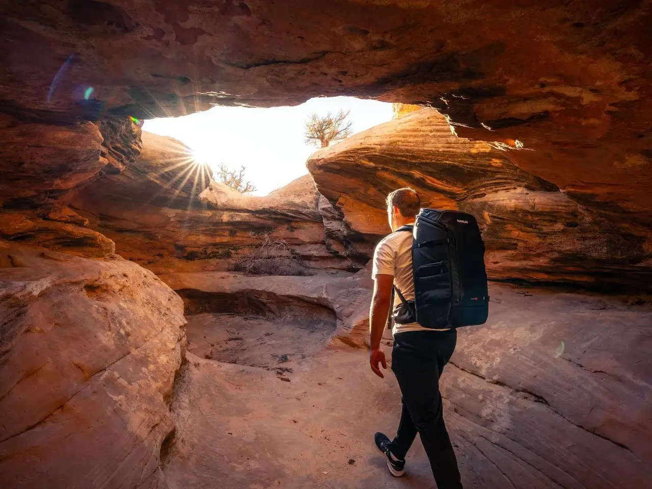 Person with a backpack exploring a rocky cave entrance