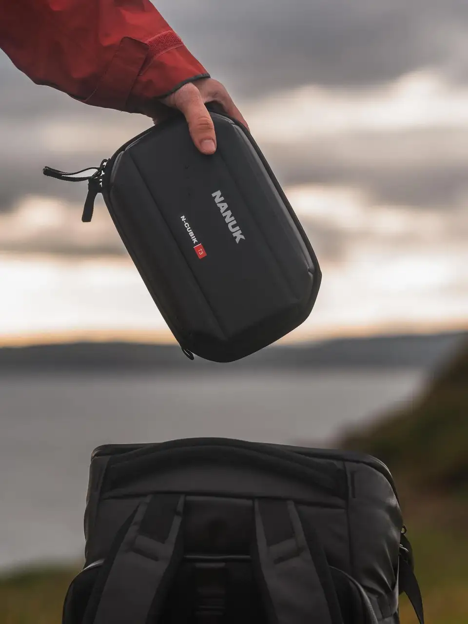 Person holding a black JunZhiJia case with a scenic background