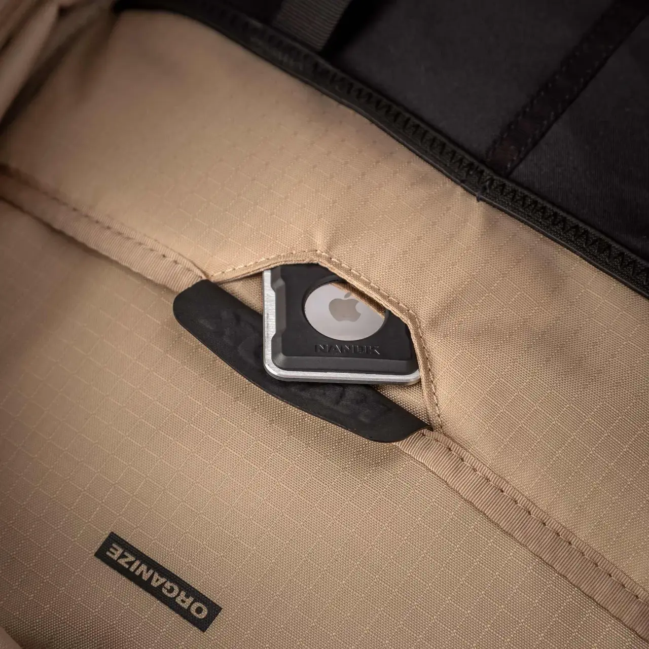Close-up of a beige bag with a black label and Apple logo, featuring the brand 'Oganize'.