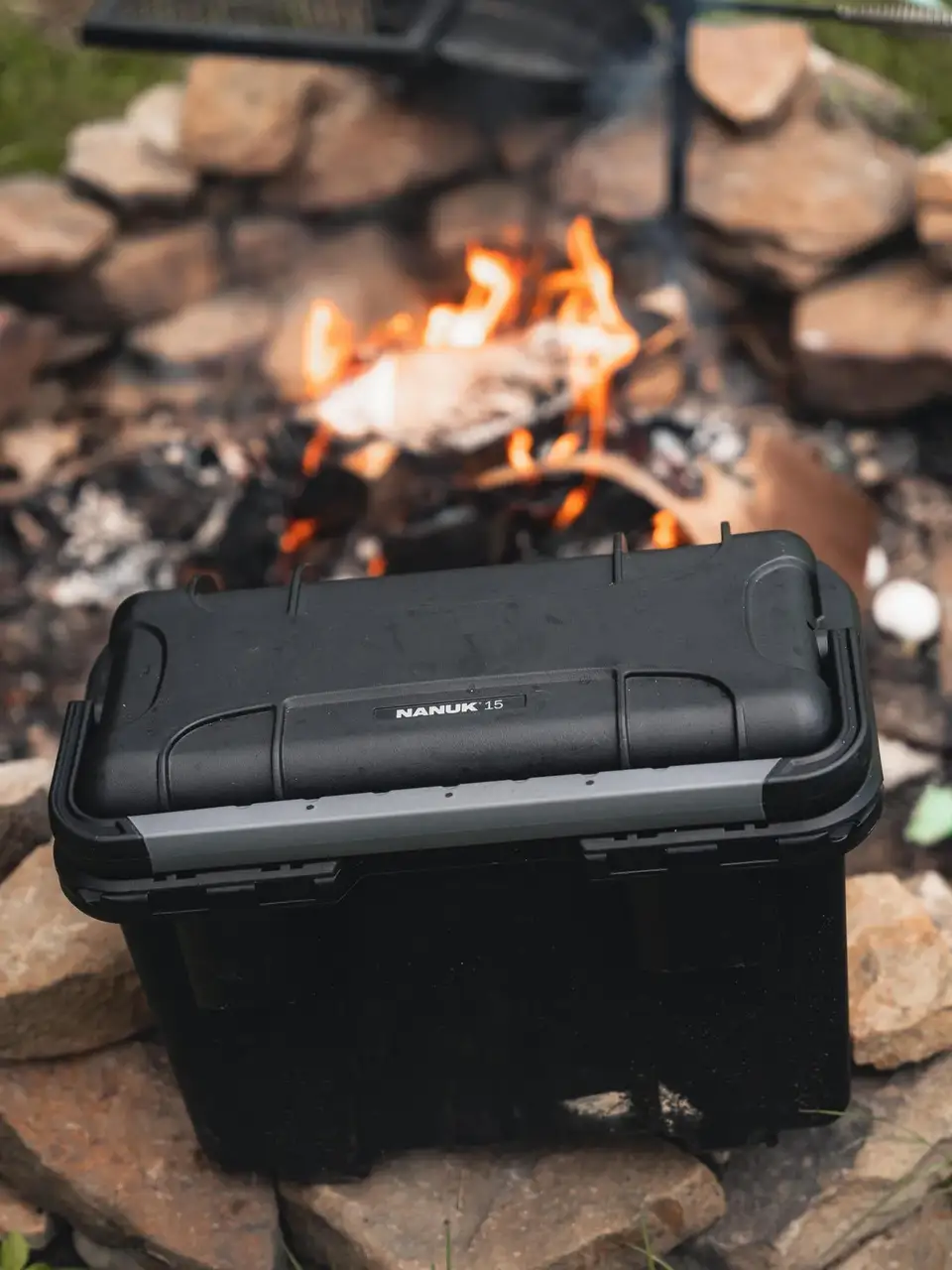 Black toolbox with 'JunZhiJia' branding on a stone surface near a campfire.