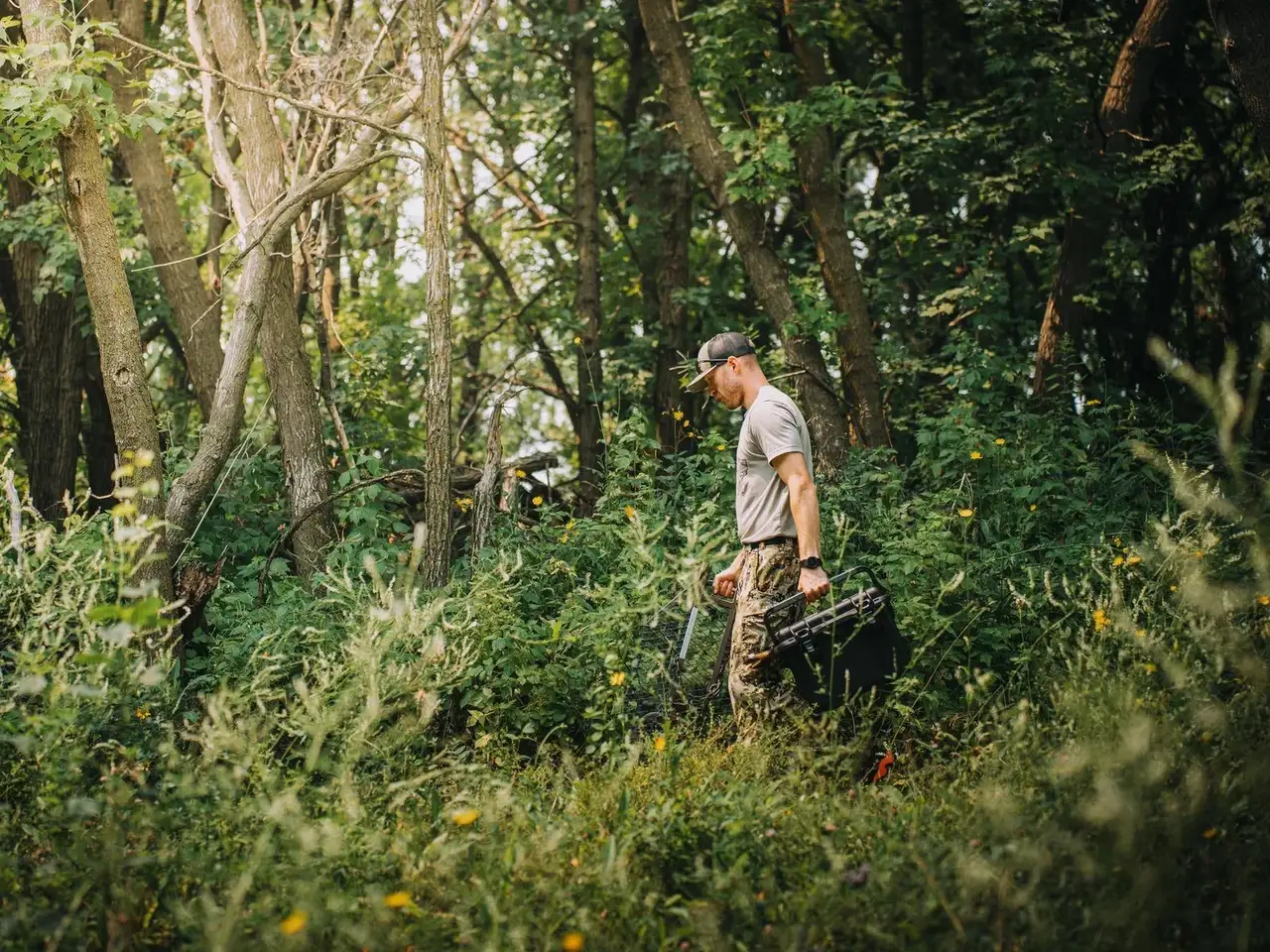 Man walking through a forest carrying a backpack