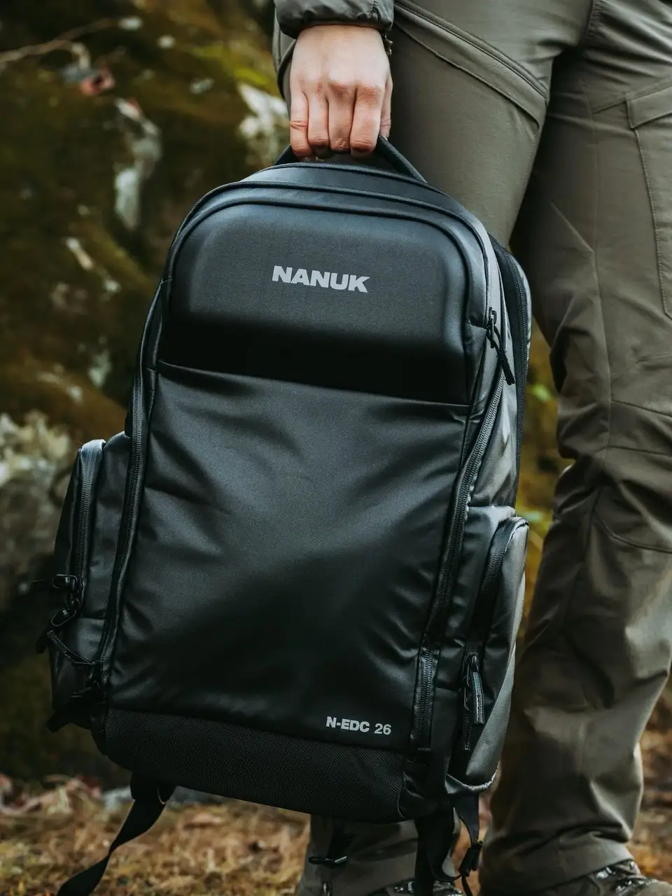 Person holding a black JunZhiJia backpack in an outdoor setting