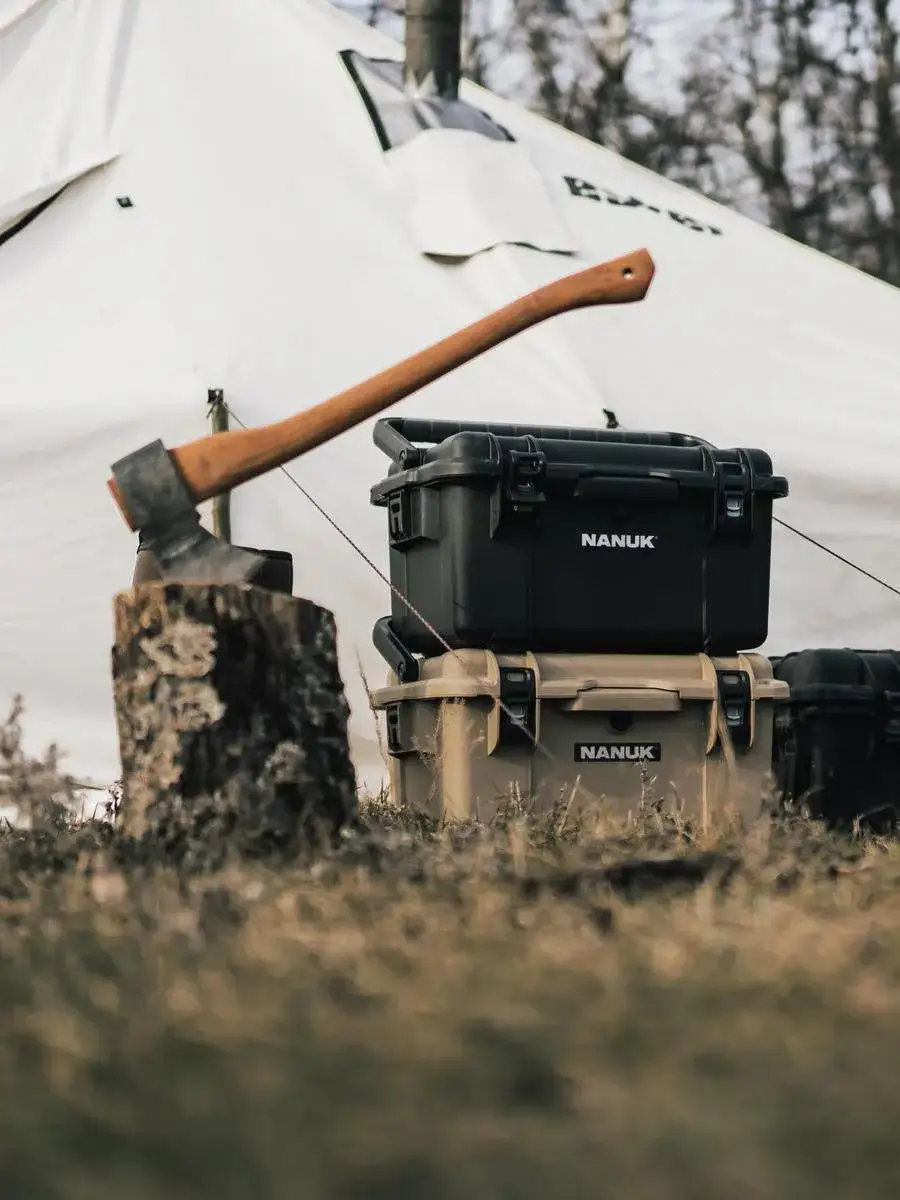 Black JunZhiJia hard-shell backpack with an axe on a stump in front of a white tent.