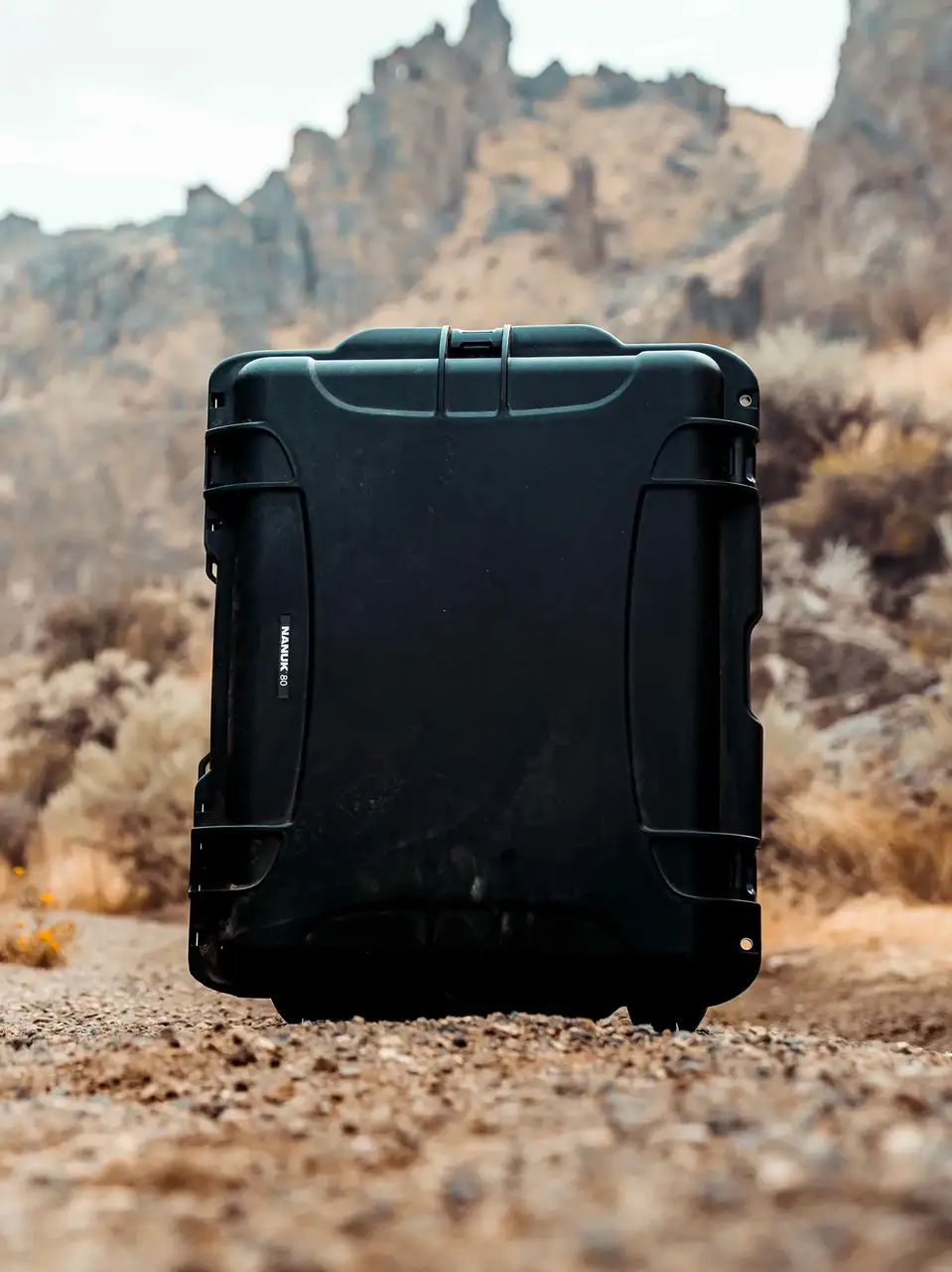 Black suitcase on a rocky terrain with mountains in the background