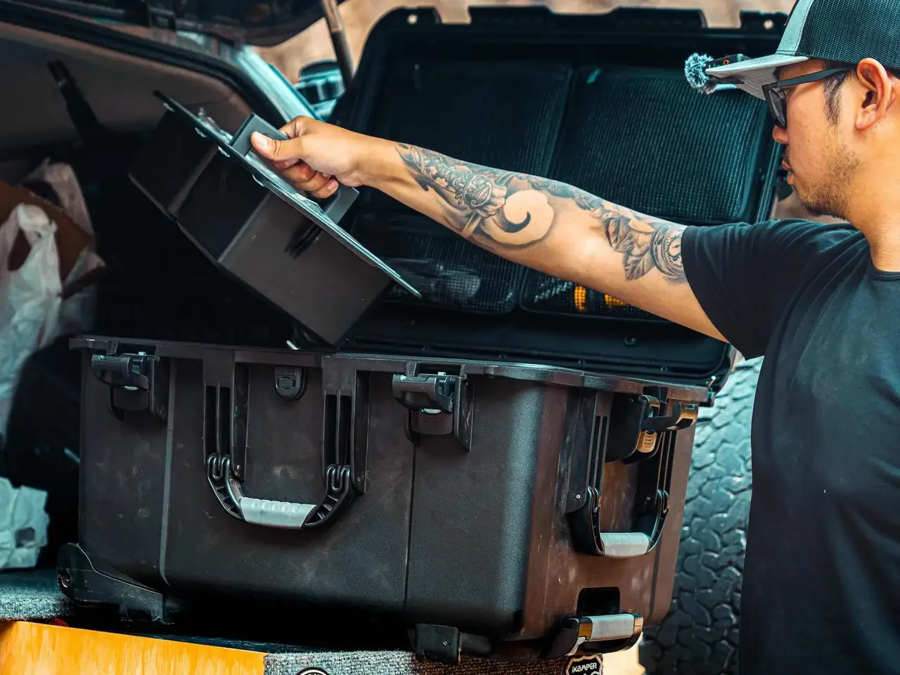 Person opening a large black suitcase in the back of a vehicle