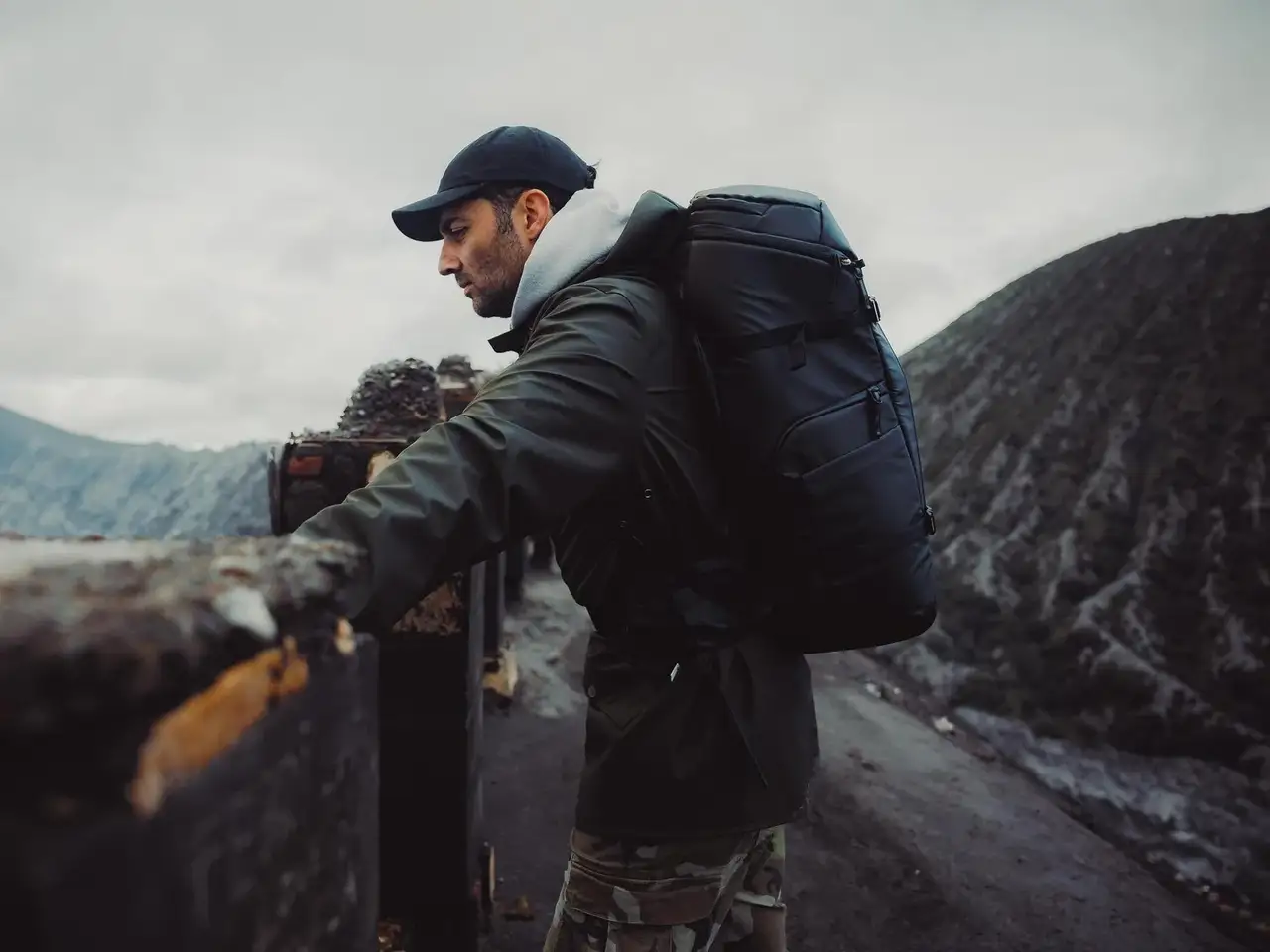 Person with a backpack standing on a mountain road with mountains in the background