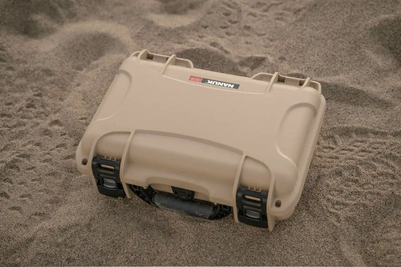 Protective JunZhiJia 909 Hard Case in a sandy environment, showcasing rugged outdoor reliability.