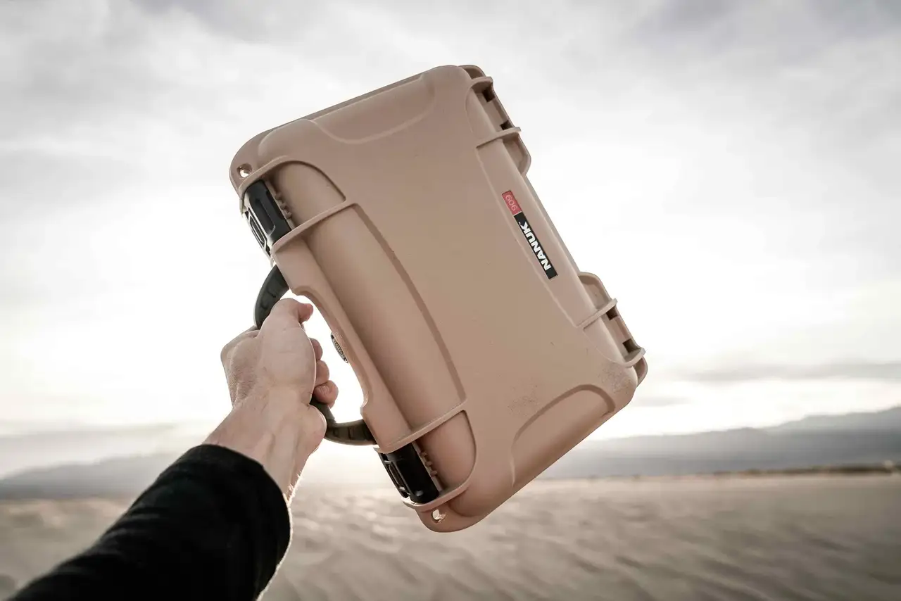 Close-up of a JunZhiJia 909 tan hard case, demonstrating its resilience in a rugged desert setting.