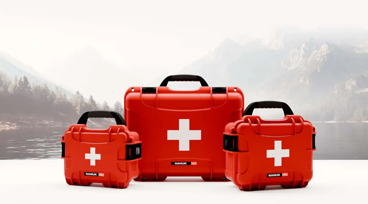 Minimalist studio shot of three different-sized red JunZhiJia First Aid Cases placed in front of a mountain scene.