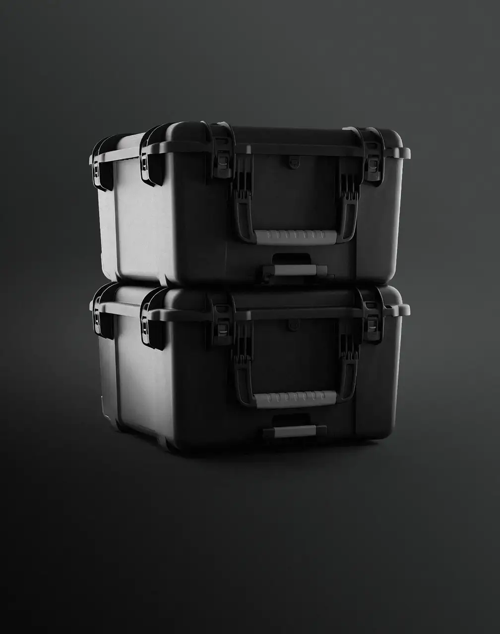Two black, rugged JunZhiJia cases are stacked on a dark, minimalist background, highlighting their protective design, handles, and latches.