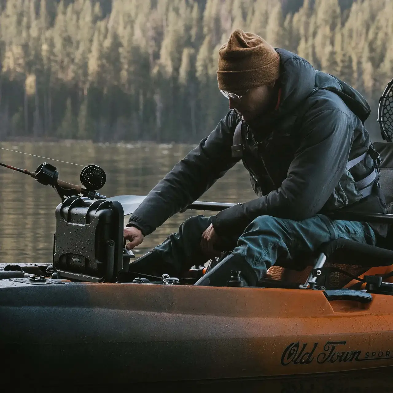 Close-up of a person fishing from a canoe, with a JunZhiJia Trail 10 case sitting on the gunwale beside them.