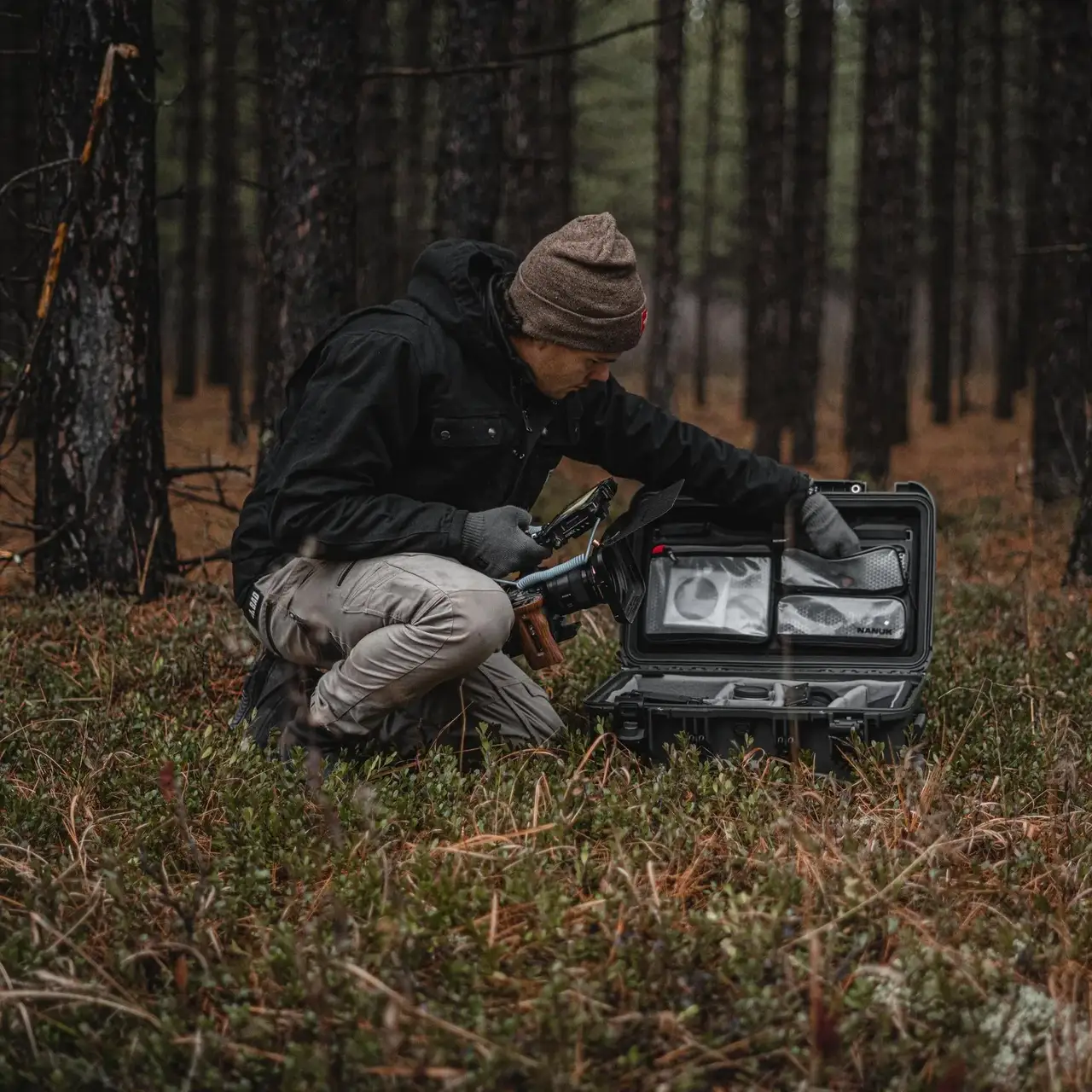 Person in a forest setting with a case containing equipment