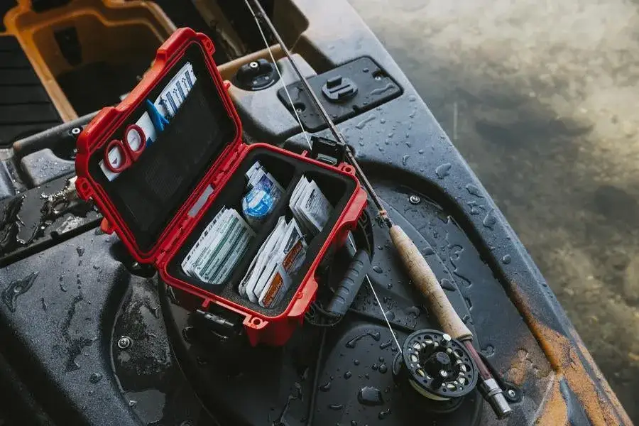 Red and black waterproof case on a kayak with fishing equipment.