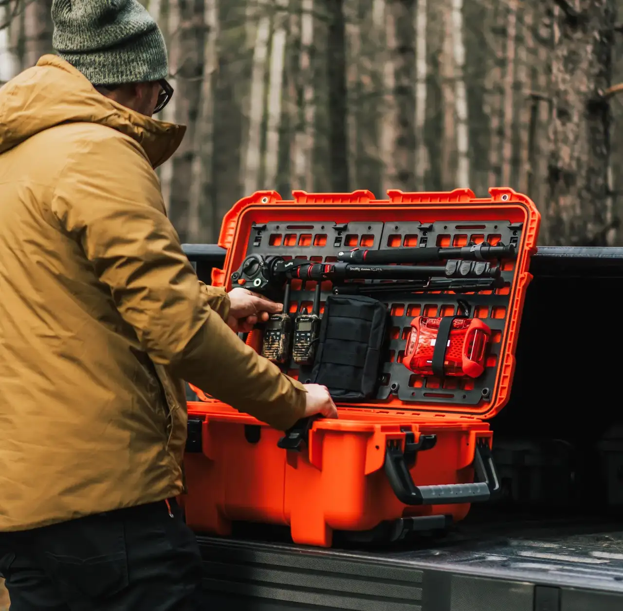 Person opening an orange toolbox in a forest setting