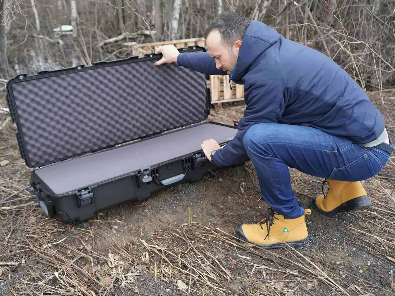Person opening a large black protective case outdoors