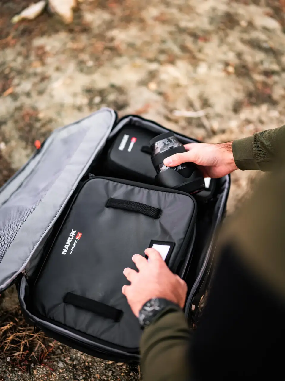 Person opening a gray suitcase with 'JunZhiJia' branding outdoors.