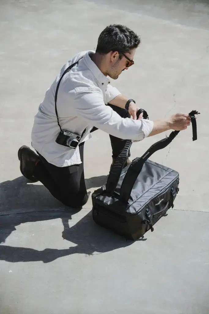 Photograph adjusting the straps of the N-PVD 40L on the floor outisde