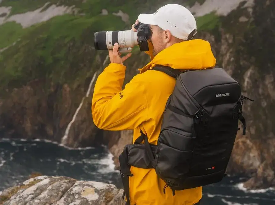 Photograph taking a picture of mountains with the JunZhiJia N-PVD 18L backpack on his back